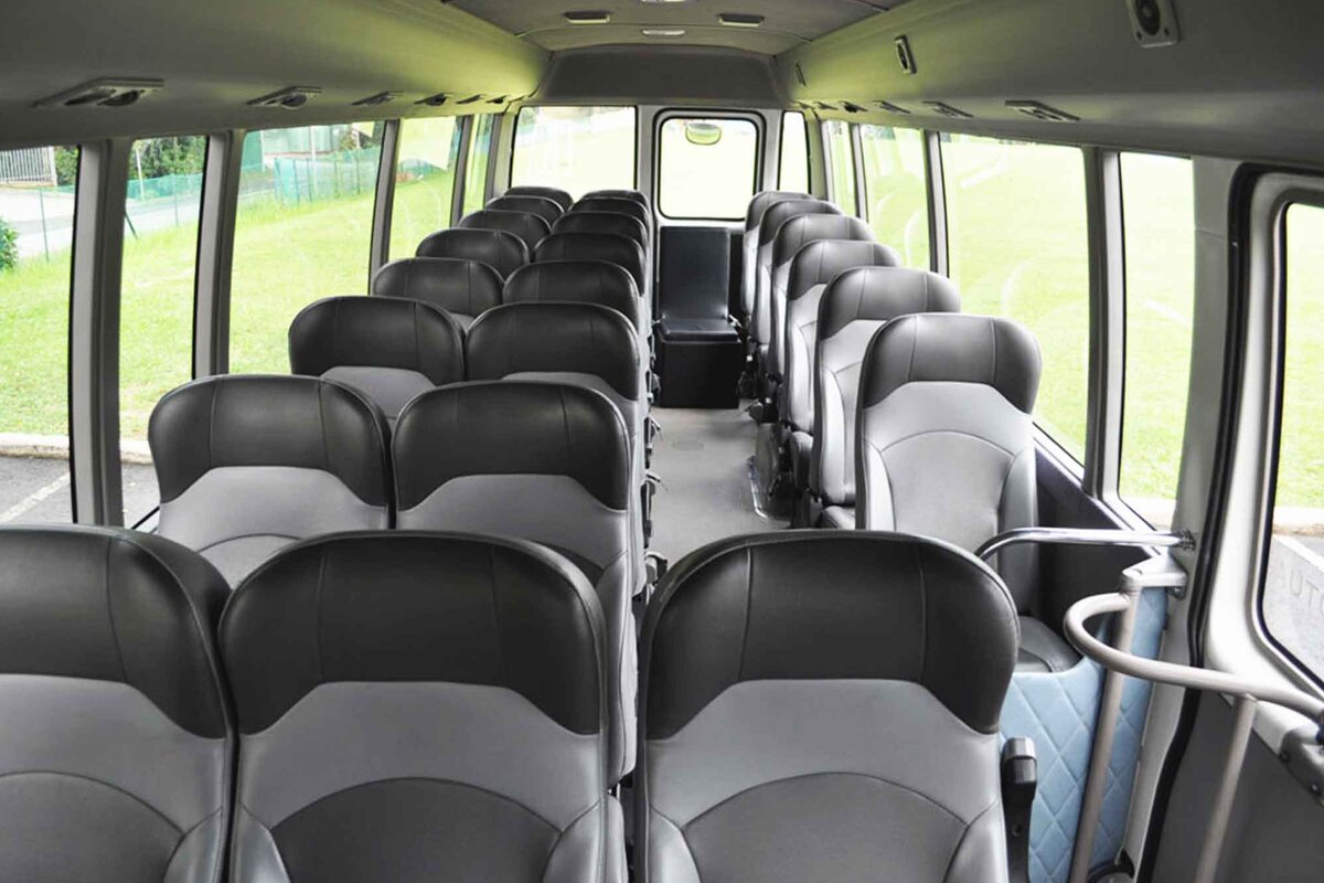 Inside a Season Bus midi bus: rows of grey seats with seat belts